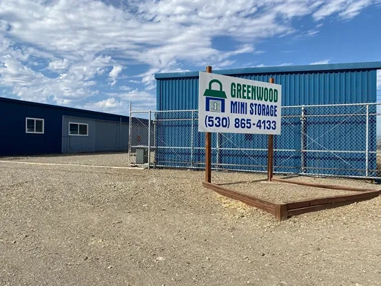 Exterior of Greenwood Mini Storage with fenced perimeter and storage units inside.
