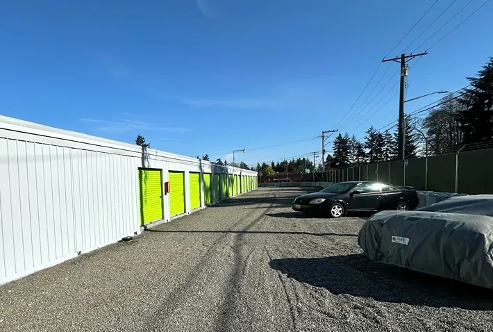 Gravel lot with uncovered parking spaces and outdoor units at Sales Road Storage facility.